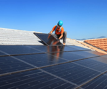 Worker in blue helmet installing solar panels